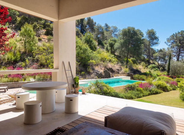 Covered outdoor lounge looking over the pool and gardens