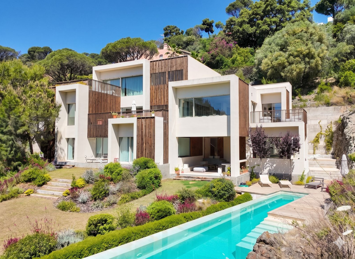 Villa exterior with infinity pool and landscaped hillside