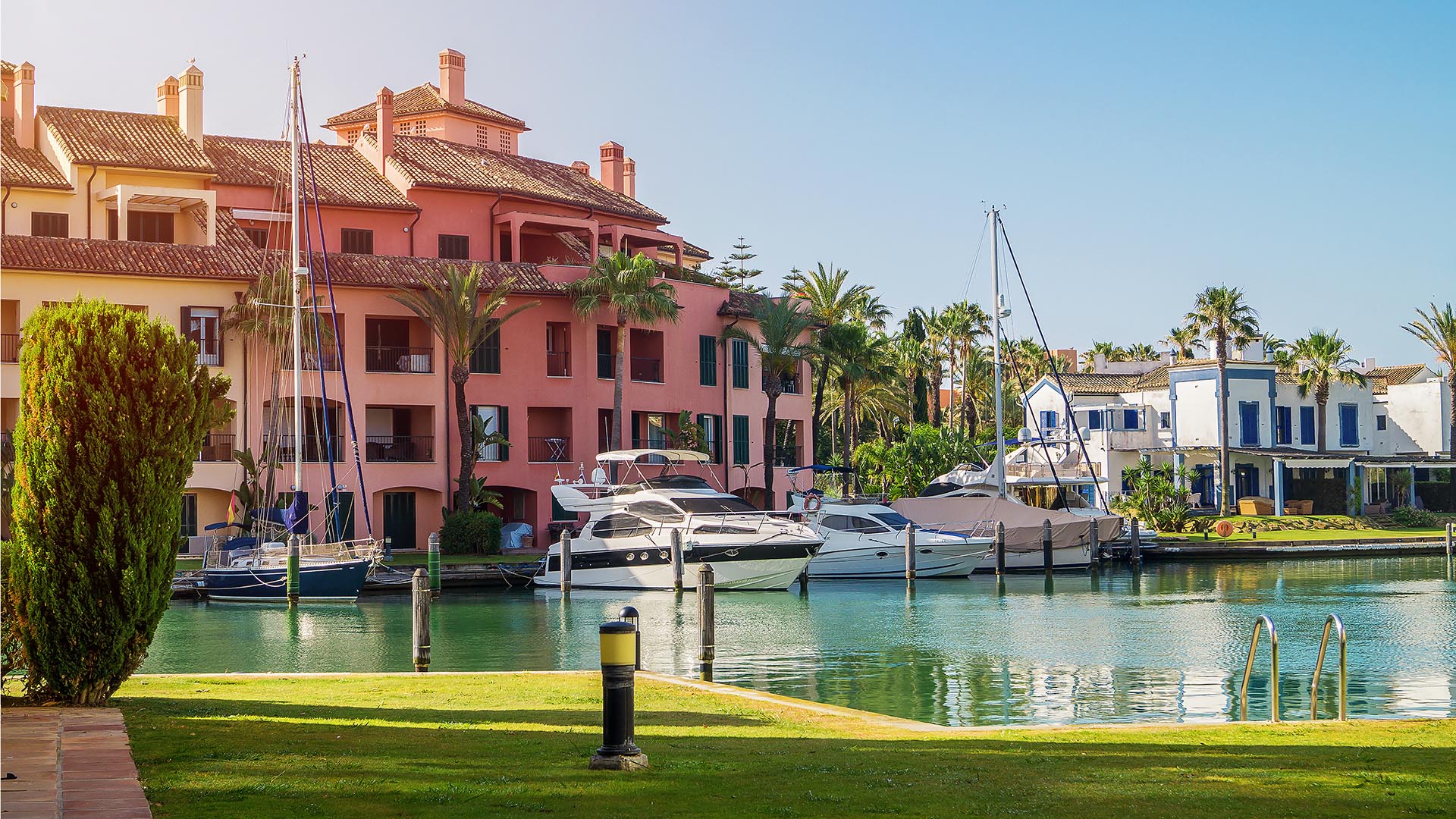 Yachts moored at Sotogrande Marina with residential buildings and palm trees behind